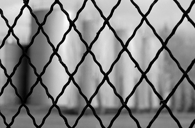 Grillage noir, une représentation floue des silos industriels.