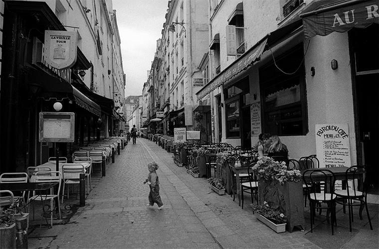 Un très jeune enfant choisit le restaurant La Vieille Tour, tandis que ses parents déjeunent en face, Paris, juillet 1987.